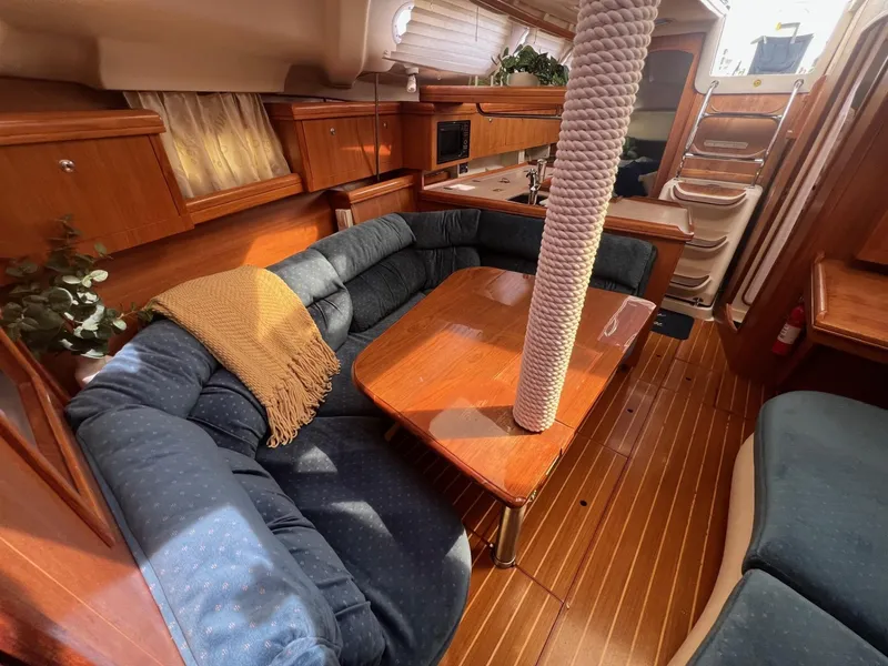 Slide: The Image of Cozy interior of 2002 Hunter 386 sailboat with wooden furnishings and blue seating. - 31