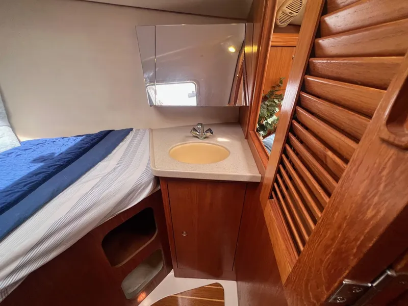 Slide: The Image of Interior of 2002 Hunter 386 sailboat with sink, mirror, and wooden cabinetry. - 32