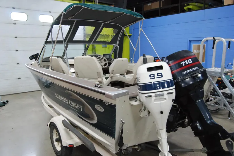Slide: The Image of 1998 Smoker Craft 178 Fazer boat with dual outboard motors in a garage setting. - 2