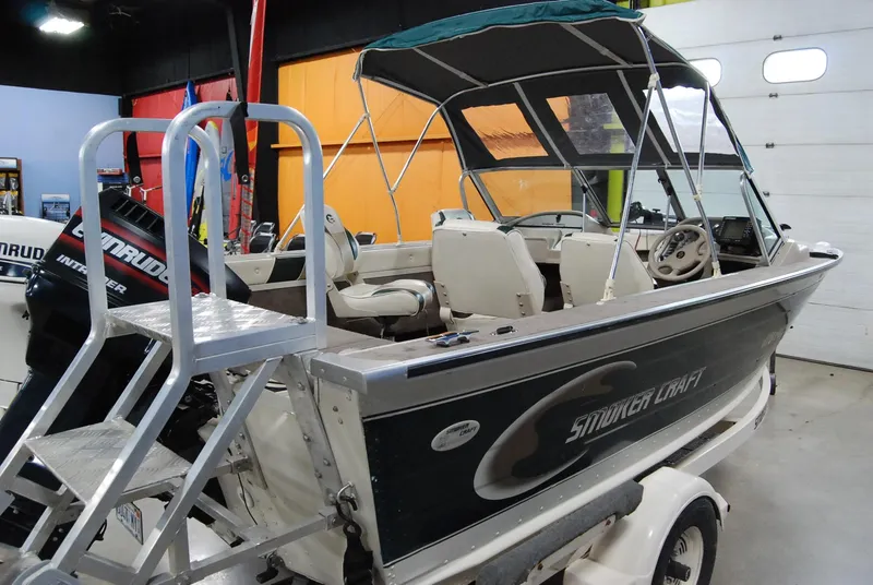 Slide: The Image of 1998 Smoker Craft 178 Fazer boat with canopy and ladder in a showroom. - 4