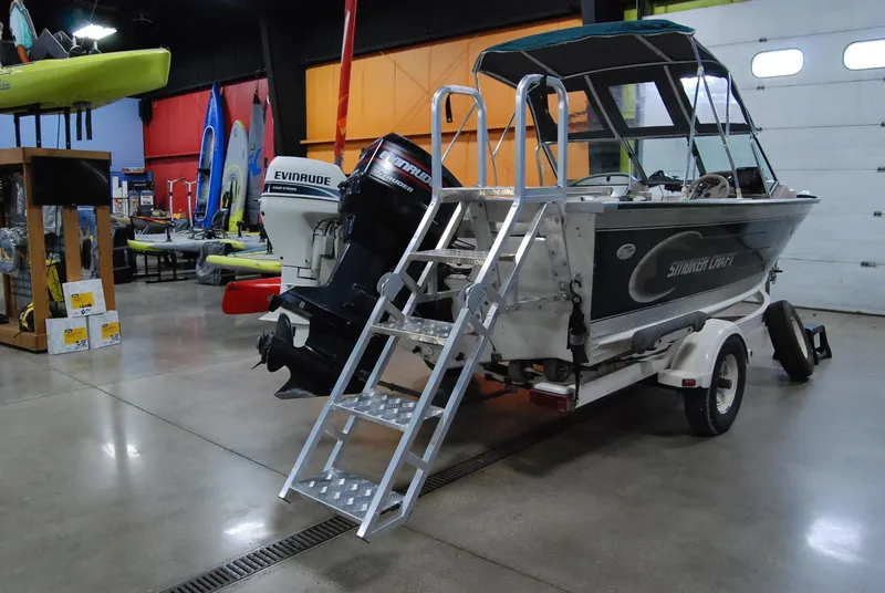Slide: The Image of 1998 Smoker Craft 178 Fazer boat with ladder, displayed indoors with colorful kayaks. - 8
