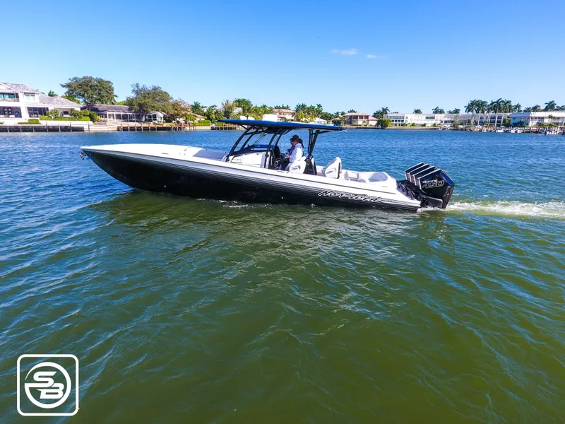 Slide: The Image of 2021 Nor-Tech 390 Sport boat cruising on a sunny day in a scenic waterfront area. - 2