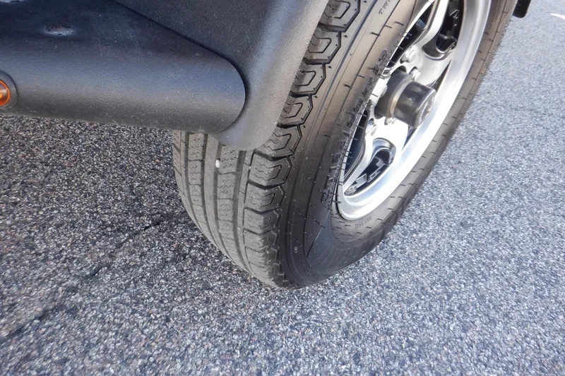 Slide: The Image of Close-up of a 2020 Alumacraft Competitor 165 Sport trailer tire on asphalt. - 7