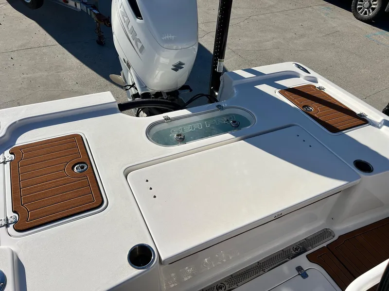 Slide: The Image of 2024 Sea Pro 250 Bay boat deck with Suzuki engine, featuring wood accents and storage compartments. - 8
