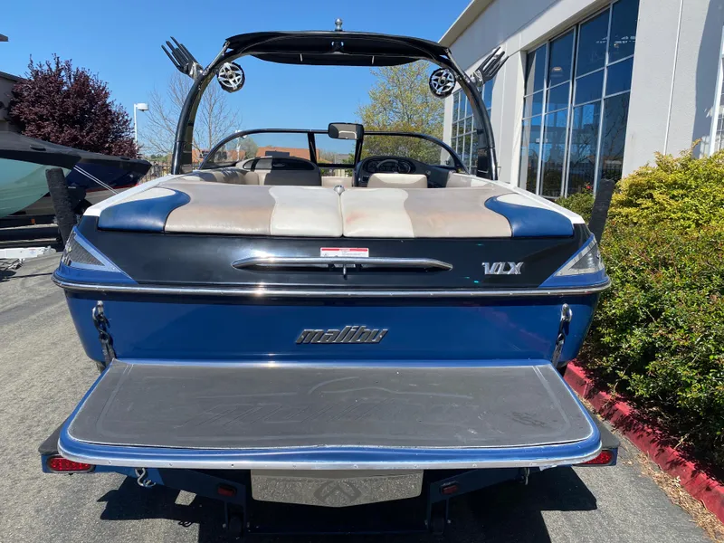 Slide: The Image of 2007 Malibu Wakesetter VLX boat, blue exterior, parked outdoors near a building. - 5
