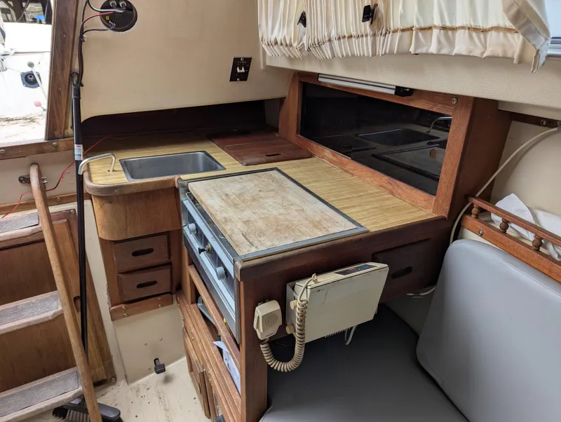 Slide: The Image of Interior of a 1983 Catalina 27 sailboat featuring a compact kitchen area. - 11
