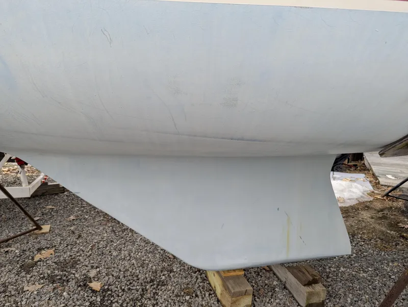 Slide: The Image of 1983 Catalina 27 sailboat keel on gravel, supported by wooden blocks. - 14