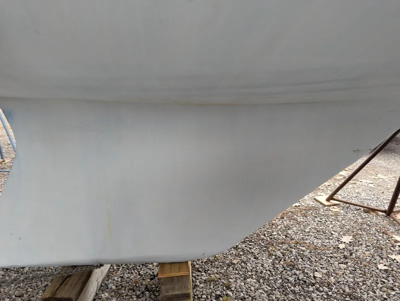 Slide: The Image of 1983 Catalina 27 sailboat hull on gravel, supported by wooden blocks. - 15