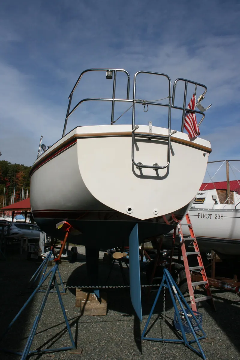 Slide: The Image of 1983 Catalina 27 sailboat on stands, with American flag, under clear sky. - 17