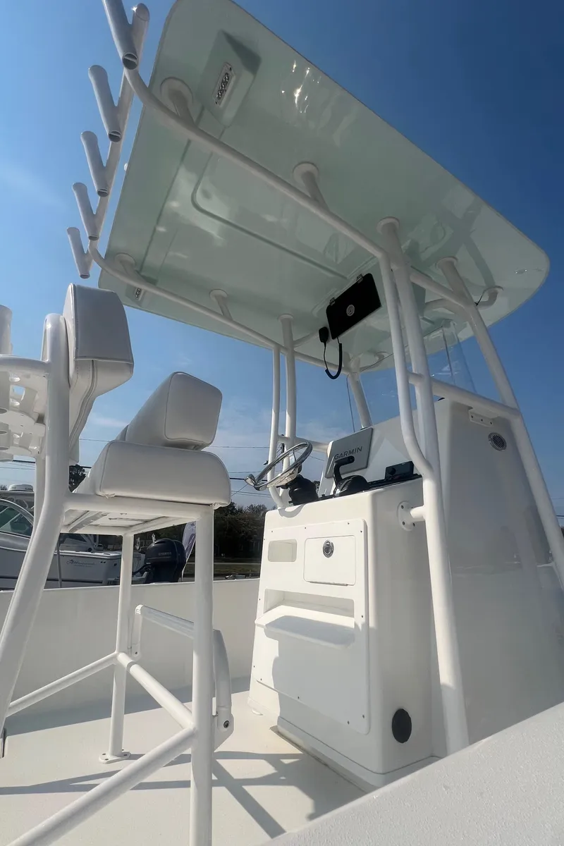 Slide: The Image of 2025 Pair Customs 24 Bay boat console with seating and canopy under clear blue sky. - 20