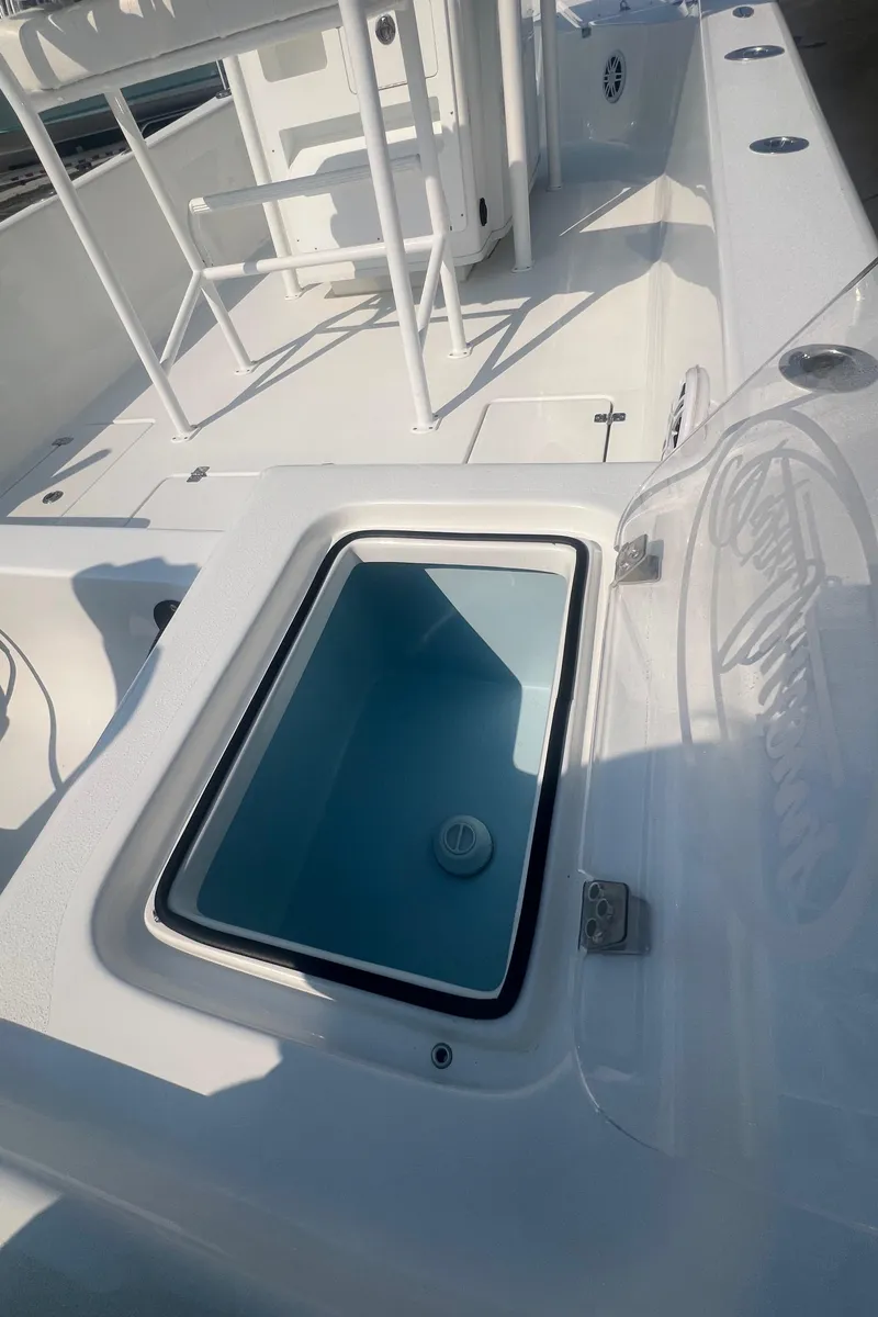 Slide: The Image of 2025 Pair Customs 24 Bay boat with open storage compartment, white deck, and sleek design. - 22
