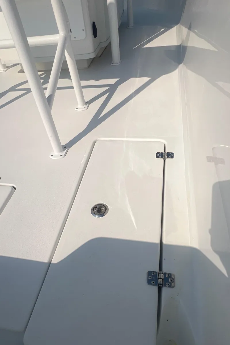 Slide: The Image of 2025 Pair Customs 24 Bay boat deck with storage compartment and railing. - 23