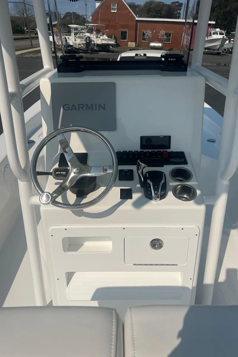 Slide: The Image of 2025 Pair Customs 24 Bay boat dashboard with Garmin navigation system and steering wheel. - 32