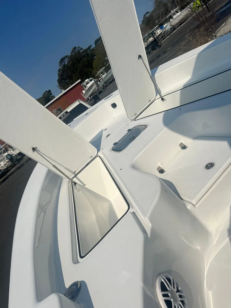 Slide: The Image of 2025 Pair Customs 24 Bay boat with open storage compartments and sleek white design. - 9