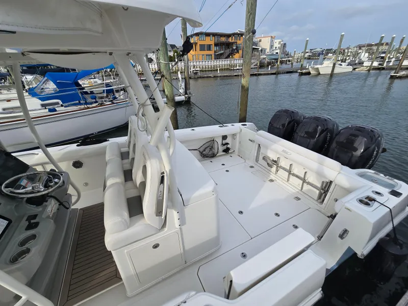 Slide: The Image of 2015 Boston Whaler 350 Outrage boat docked, featuring spacious deck and triple outboard engines. - 12