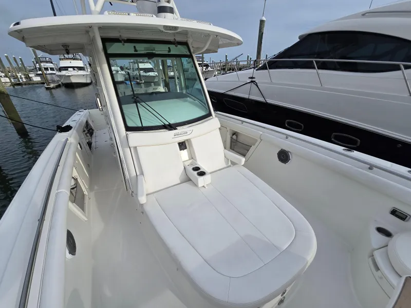 Slide: The Image of 2015 Boston Whaler 350 Outrage boat docked, showcasing sleek design and spacious deck. - 19