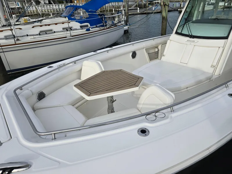 Slide: The Image of Boston Whaler 350 Outrage 2015 boat with spacious seating and table in marina setting. - 21