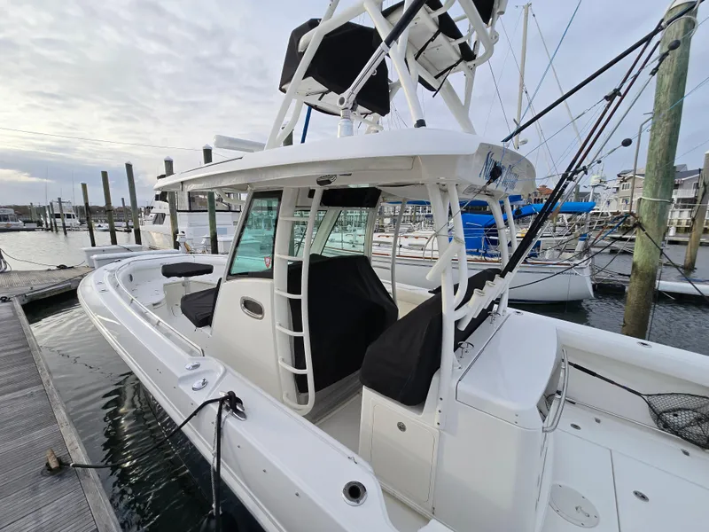 Slide: The Image of 2015 Boston Whaler 350 Outrage docked at marina, showcasing sleek design and spacious deck. - 28
