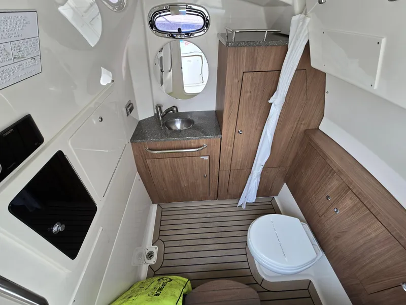 Slide: The Image of 2015 Boston Whaler 350 Outrage cabin interior with sink, toilet, and wood cabinetry. - 9