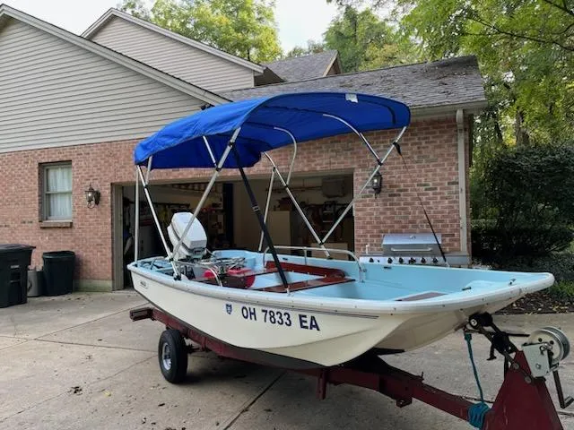 Slide: The Image of 1964 Boston Whaler 13 Sport boat with blue canopy on trailer in driveway. - 0