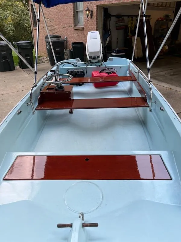 Slide: The Image of 1964 Boston Whaler 13 Sport boat with wooden seats and outboard motor in a driveway. - 1
