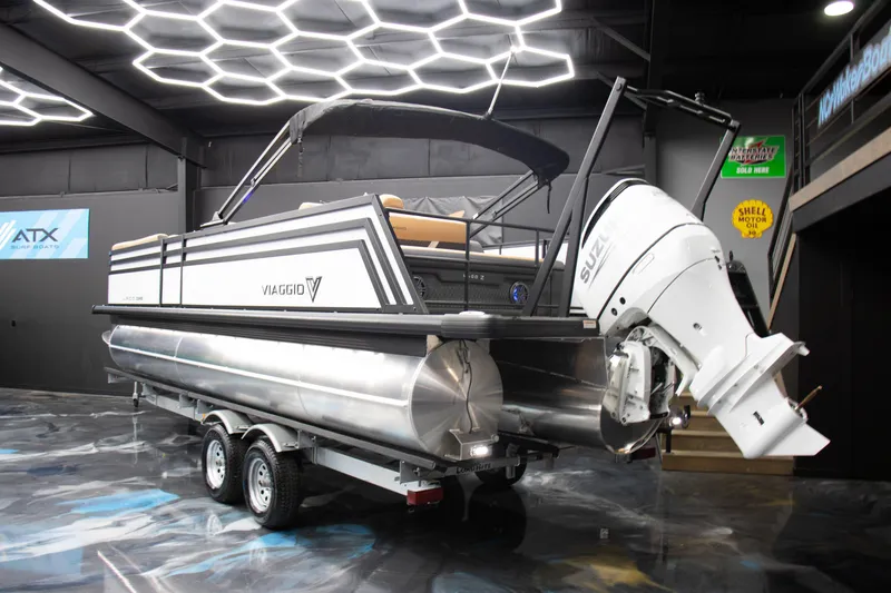 Slide: The Image of 2025 Viaggio Lago Z-S pontoon boat on trailer in modern showroom. - 10