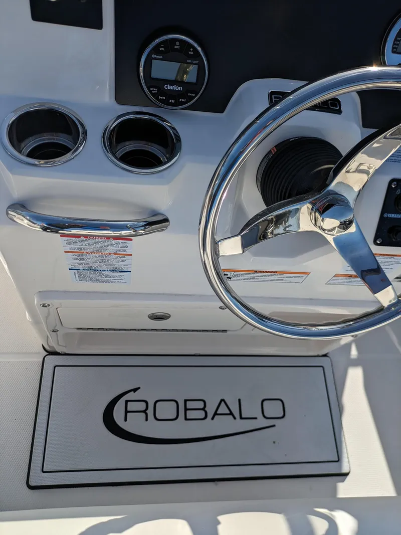 Slide: The Image of 2025 Robalo R180 Center Console boat dashboard with steering wheel and cup holders. - 13