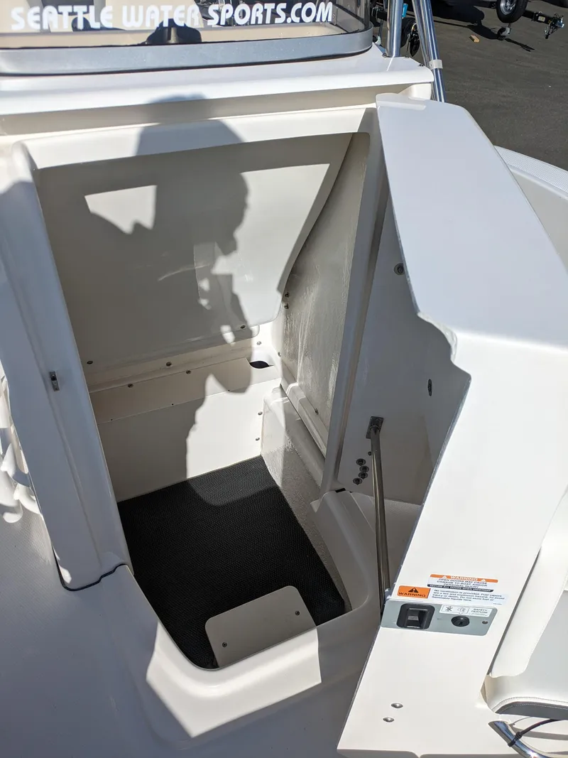 Slide: The Image of 2025 Robalo R180 Center Console boat storage compartment, open hatch, white interior. - 20