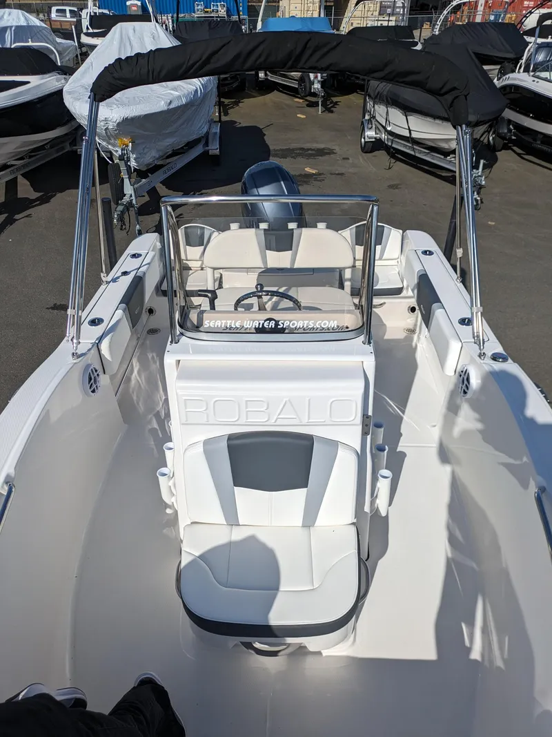 Slide: The Image of 2025 Robalo R180 Center Console boat with seating and canopy in a marina setting. - 23