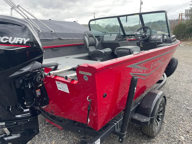 Slide: The Image of 2025 Lund 1650 Rebel XL Sport boat, red exterior, on a trailer with Mercury engine. - 16