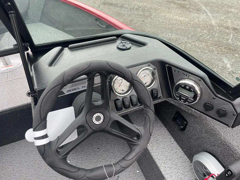 Slide: The Image of 2025 Lund 1650 Rebel XL Sport boat dashboard with steering wheel and gauges. - 22
