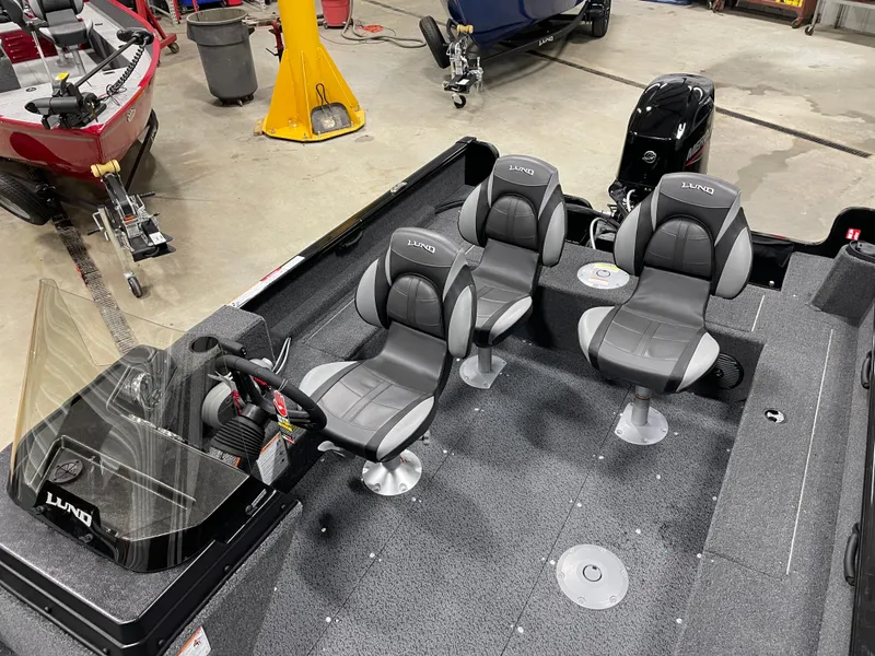 Slide: The Image of 2025 Lund 1650 Rebel XL Blackout boat interior with three gray seats and steering console. - 11