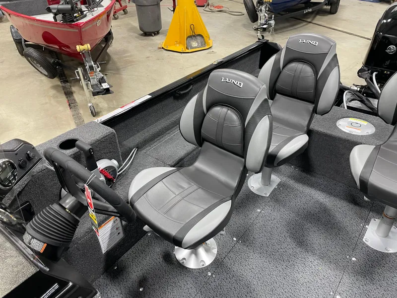 Slide: The Image of 2025 Lund 1650 Rebel XL Blackout boat interior with gray seating and steering console. - 5