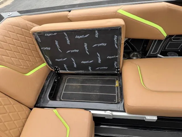 Slide: The Image of 2022 Tigé 24 RZK boat interior with tan seats and storage compartment. - 12