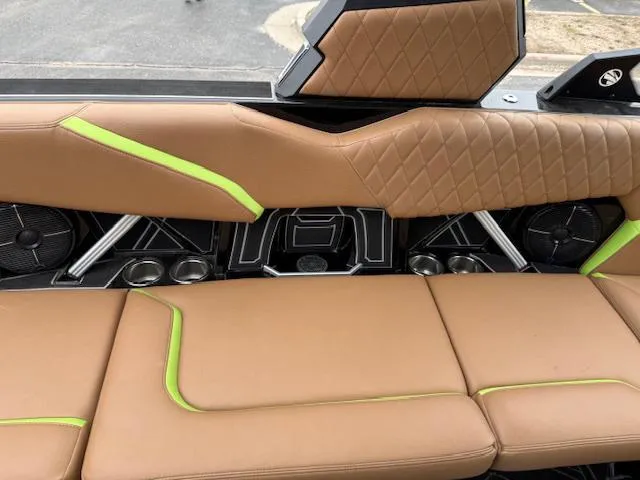 Slide: The Image of 2022 Tigé 24 RZK boat interior with brown and green upholstery, featuring speakers and cup holders. - 13