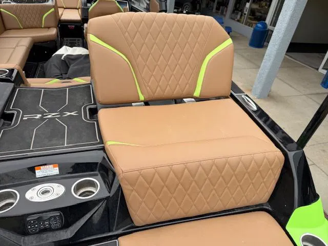 Slide: The Image of 2022 Tigé 24 RZK boat interior with tan and green seating, cup holders, and RZX branding. - 6