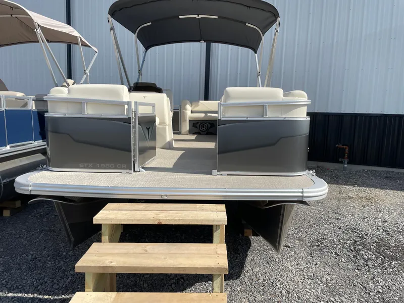 Slide: The Image of 2025 Tahoe Pontoon 1980 STX CRUISE boat with canopy, docked on gravel. - 2