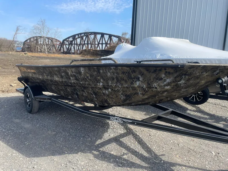 Slide: The Image of 2025 Excel 1751 River Warrior boat on trailer near bridge and building. - 23
