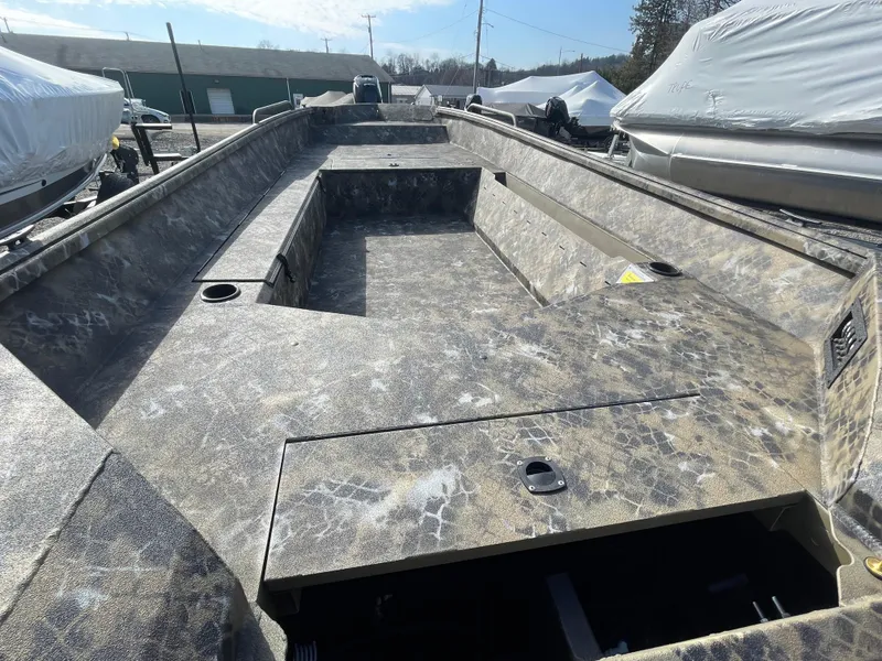 Slide: The Image of 2025 Excel 1751 River Warrior boat interior with camouflage design, docked outdoors. - 9