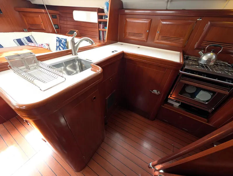 Slide: The Image of 2003 Beneteau Oceanis 473 yacht kitchen with wooden cabinetry, sink, and stove. - 15