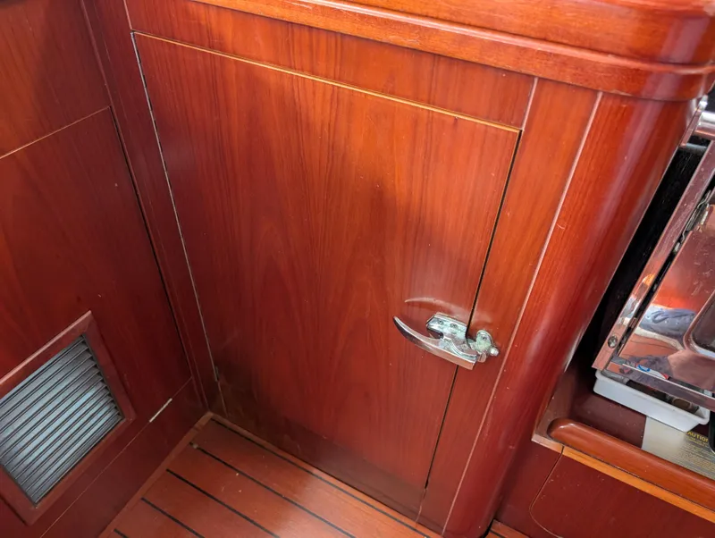 Slide: The Image of Wooden interior of 2003 Beneteau Oceanis 473 sailboat, featuring a cabinet with a metal latch. - 18