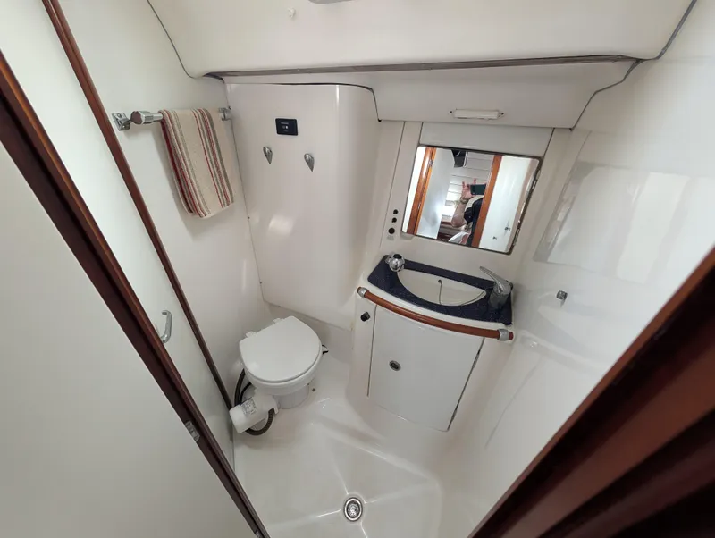 Slide: The Image of Bathroom interior of 2003 Beneteau Oceanis 473 yacht, featuring toilet, sink, and mirror. - 27