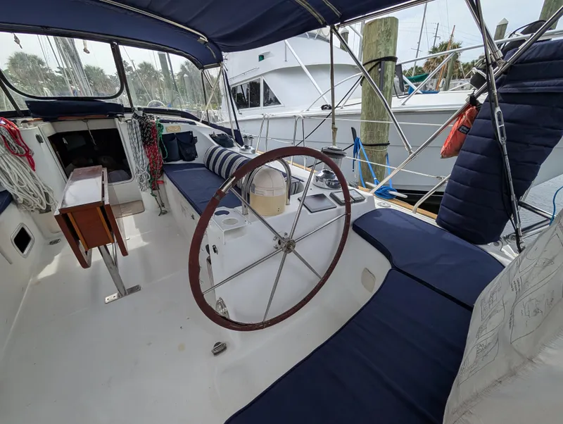 Slide: The Image of Cockpit of 2003 Beneteau Oceanis 473 sailboat with blue seating and wooden steering wheel. - 32