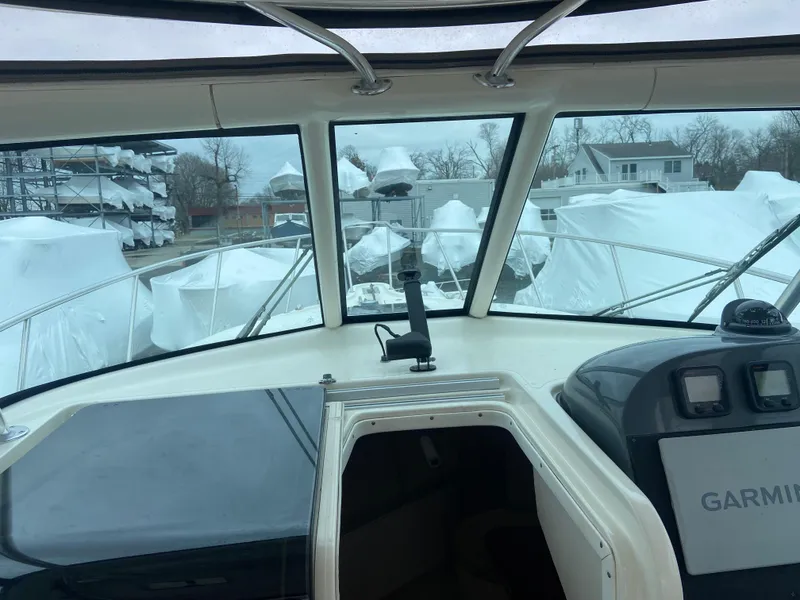 Slide: The Image of 2007 Pursuit 335 Offshore boat interior with Garmin navigation, docked with covered boats visible outside. - 32