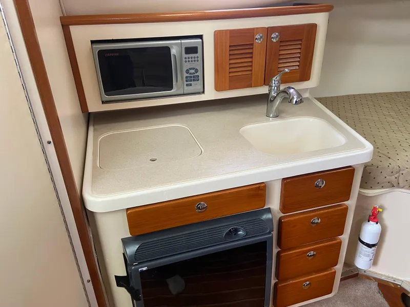Slide: The Image of 2007 Pursuit 335 Offshore kitchenette with microwave, sink, and storage drawers. - 34