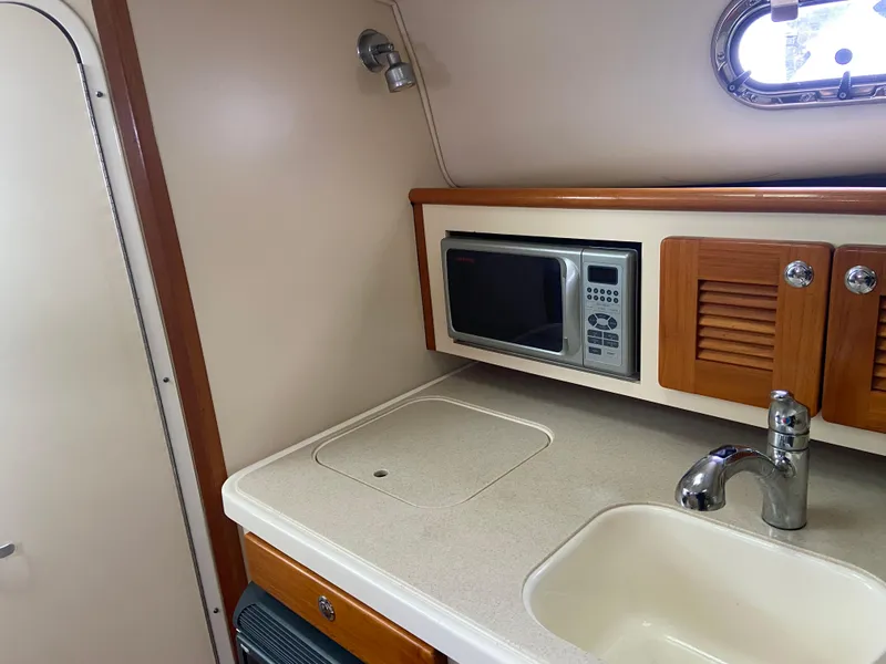 Slide: The Image of 2007 Pursuit 335 Offshore boat kitchen with microwave, sink, and storage cabinets. - 35