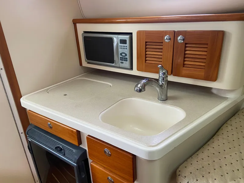 Slide: The Image of 2007 Pursuit 335 Offshore boat kitchenette with sink, microwave, and wooden cabinets. - 36