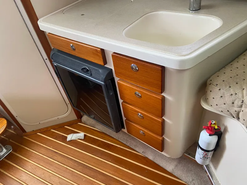 Slide: The Image of 2007 Pursuit 335 Offshore cabin with sink, wooden drawers, and fire extinguisher. - 38