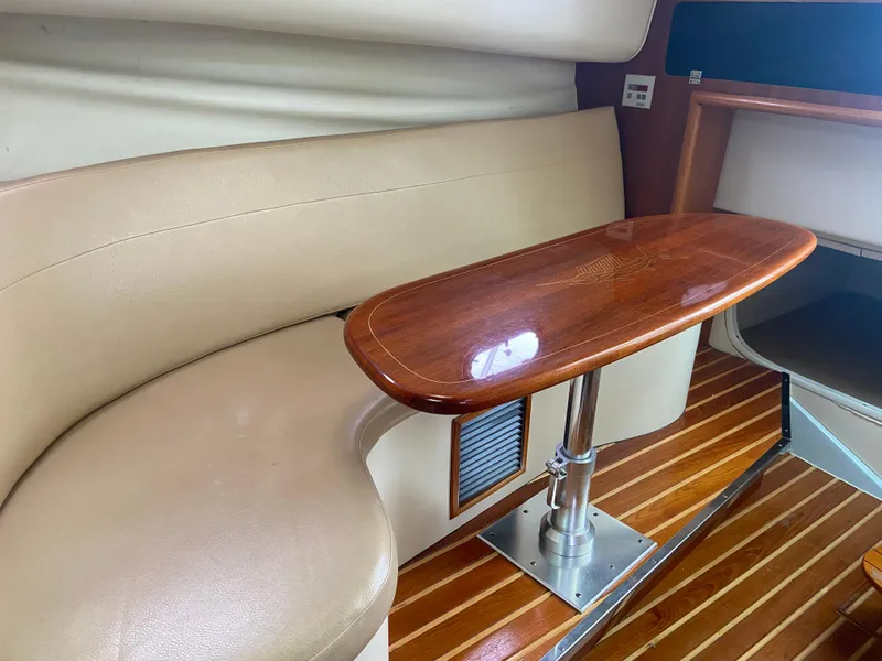 Slide: The Image of 2007 Pursuit 335 Offshore cabin interior with wooden table and beige seating. - 45