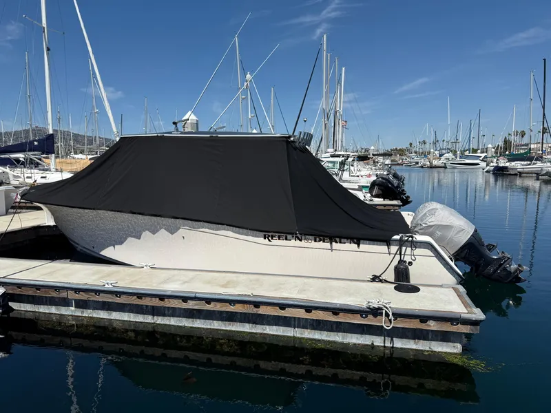 Slide: The Image of 2005 Grady-White Bimini 306 boat docked with cover, surrounded by marina and sailboats. - 17